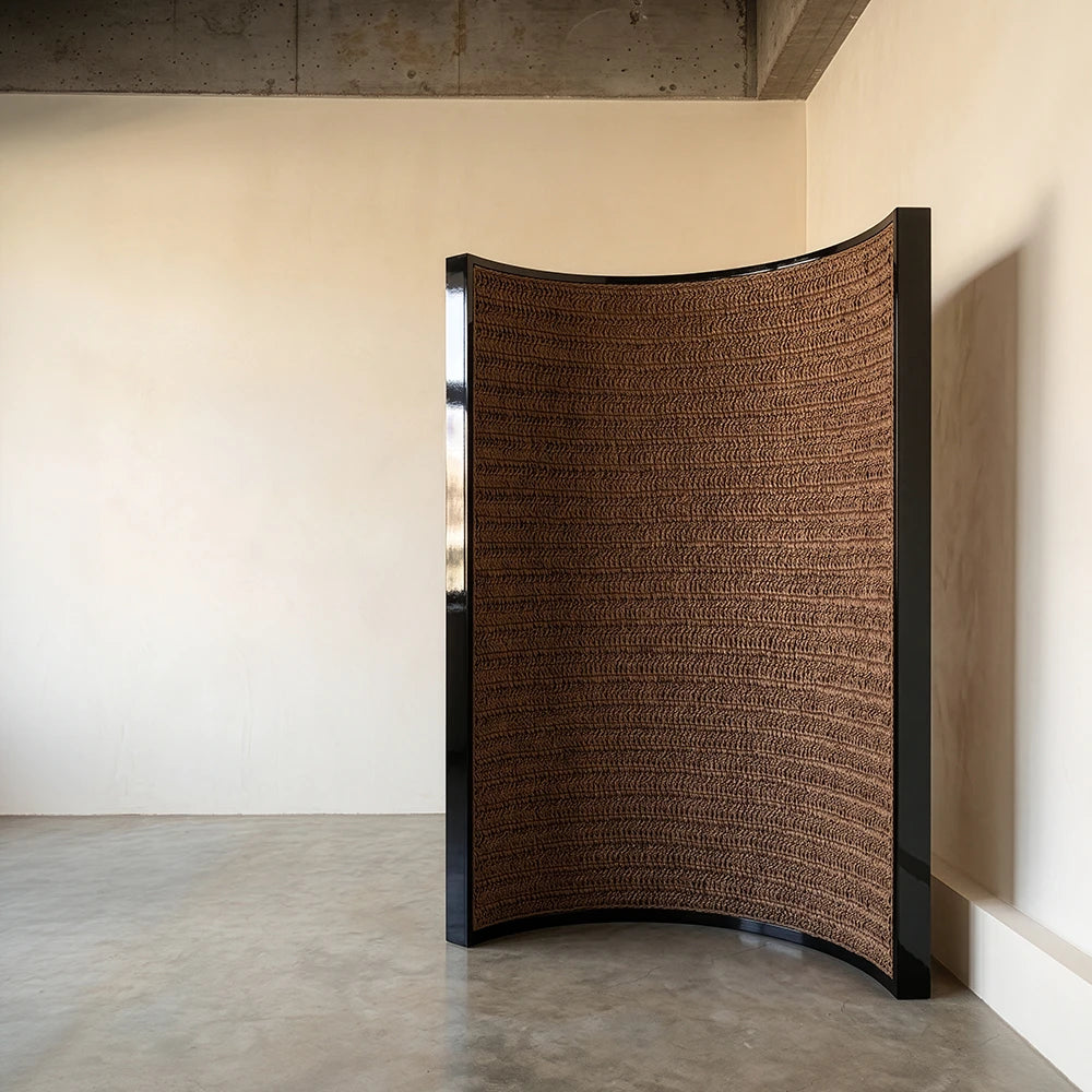 Interior view of The Veil Room Screen by Studio Romell, revealing a curved panel entirely handwoven in textured brown raffia.